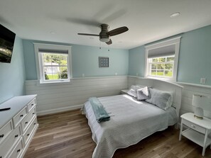 A bedroom with a bed, dresser, nightstand, and ceiling fan.
