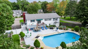 Une propriété résidentielle dotée d’une piscine, d’un patio couvert et d’une pelouse bien entretenue.