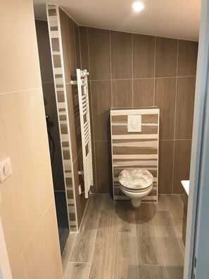 Une salle de bain comprenant des toilettes, un porte-serviettes et un espace douche.
