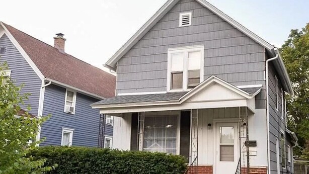 A two-story house with a front porch, a chimney, and a well-maintained lawn. - 2-bedroom in quiet neighborhood -- monthly rental perfect for traveling workers! (St. Joseph)