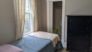 A bedroom with a bed, a dresser, a window with curtains, and a closet. - 2-bedroom in quiet neighborhood -- monthly rental perfect for traveling workers! (St. Joseph)