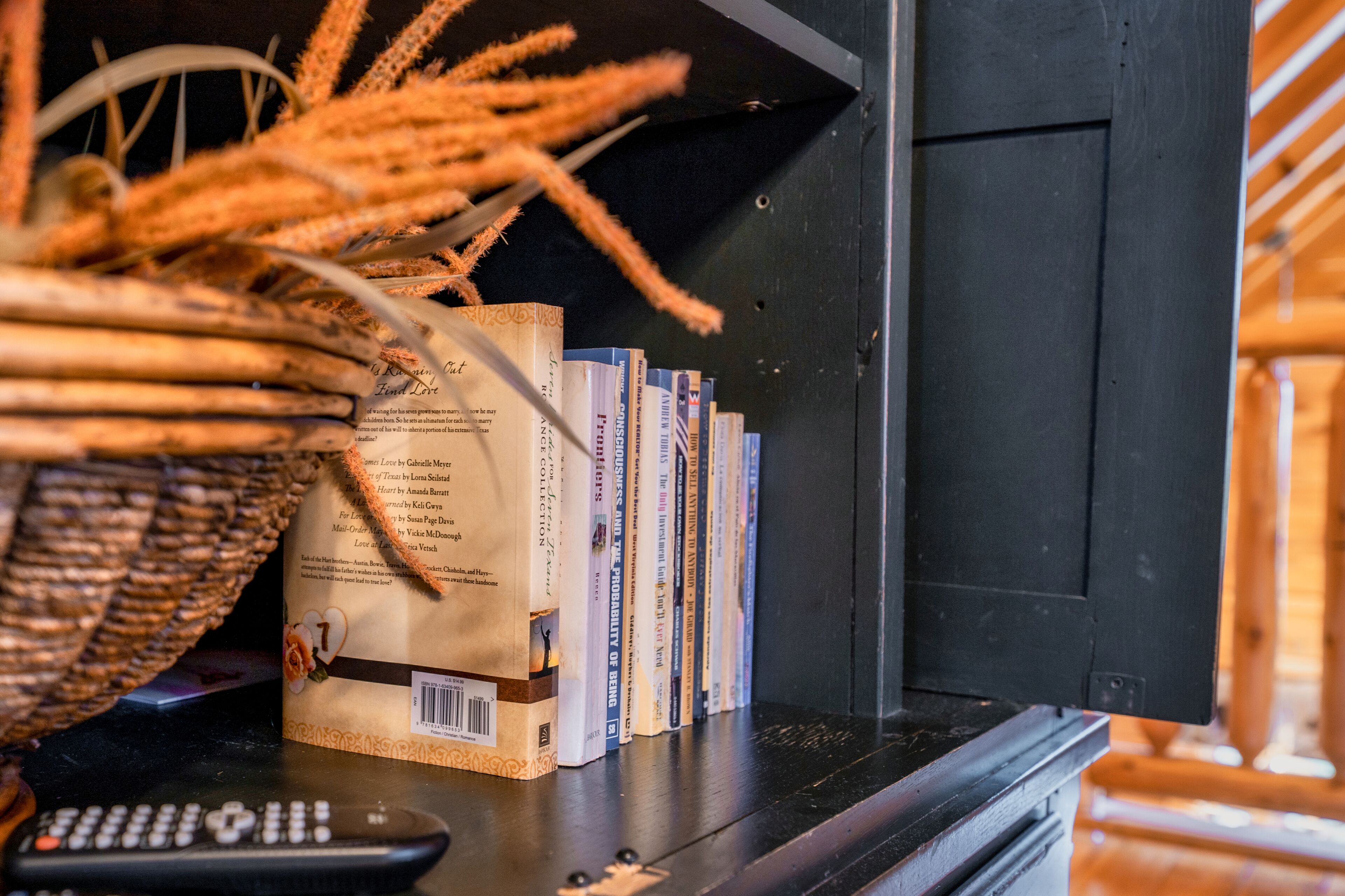 Una libreria con libri e un telecomando.