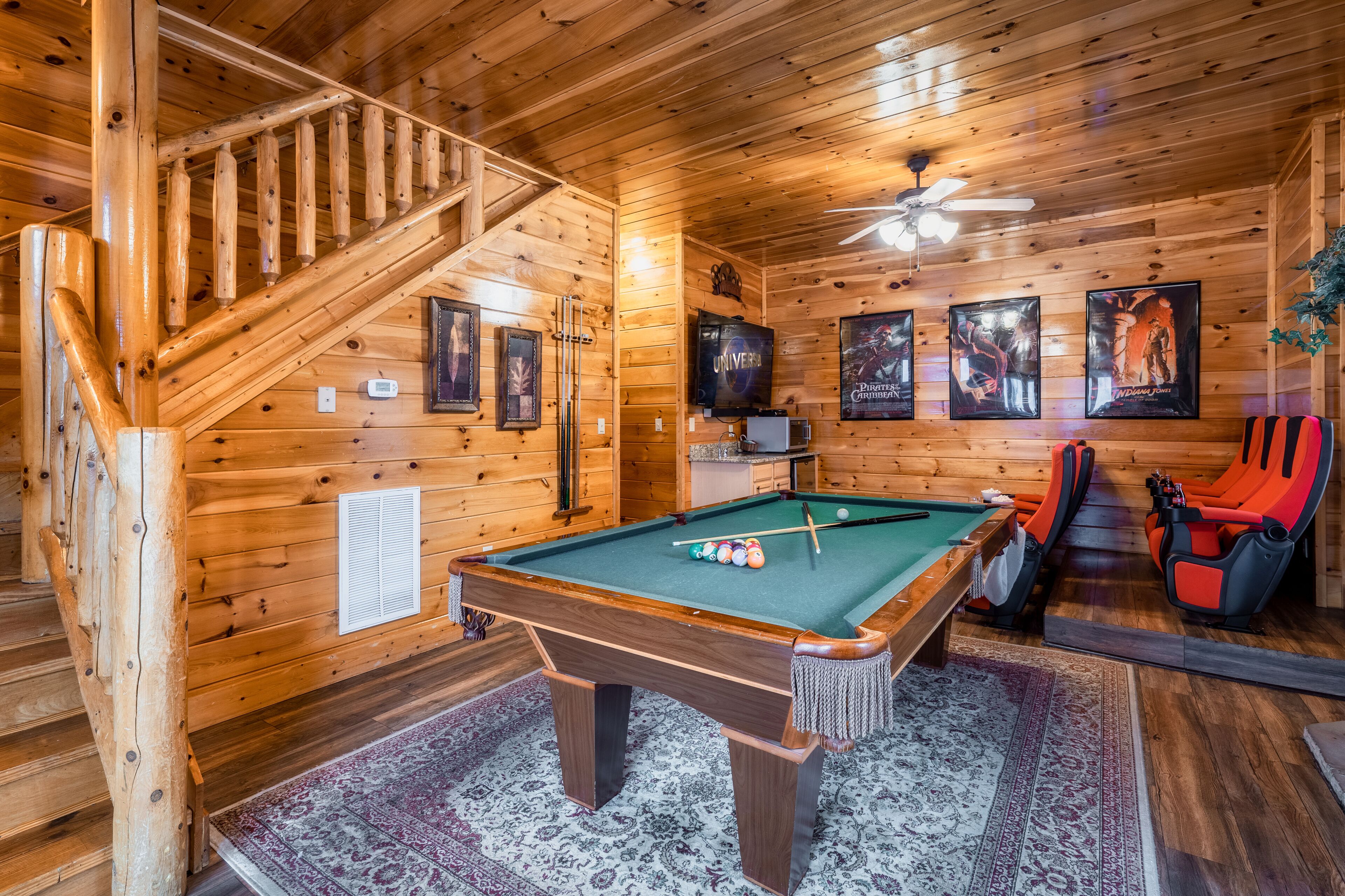 A wooden interior with a pool table, pool cues, and a ceiling fan.