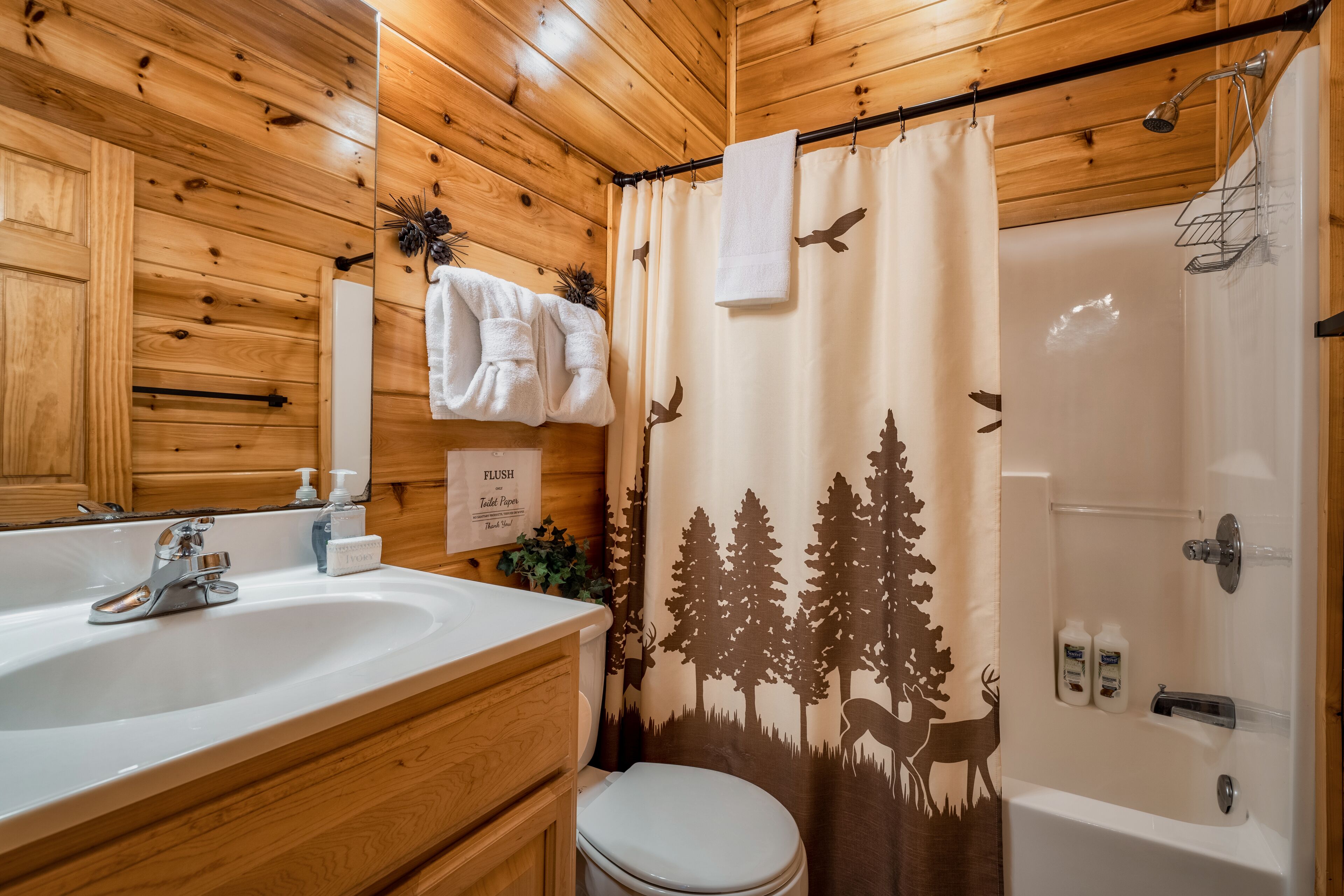 A wooden cabin bathroom with a sink, toilet, and shower.