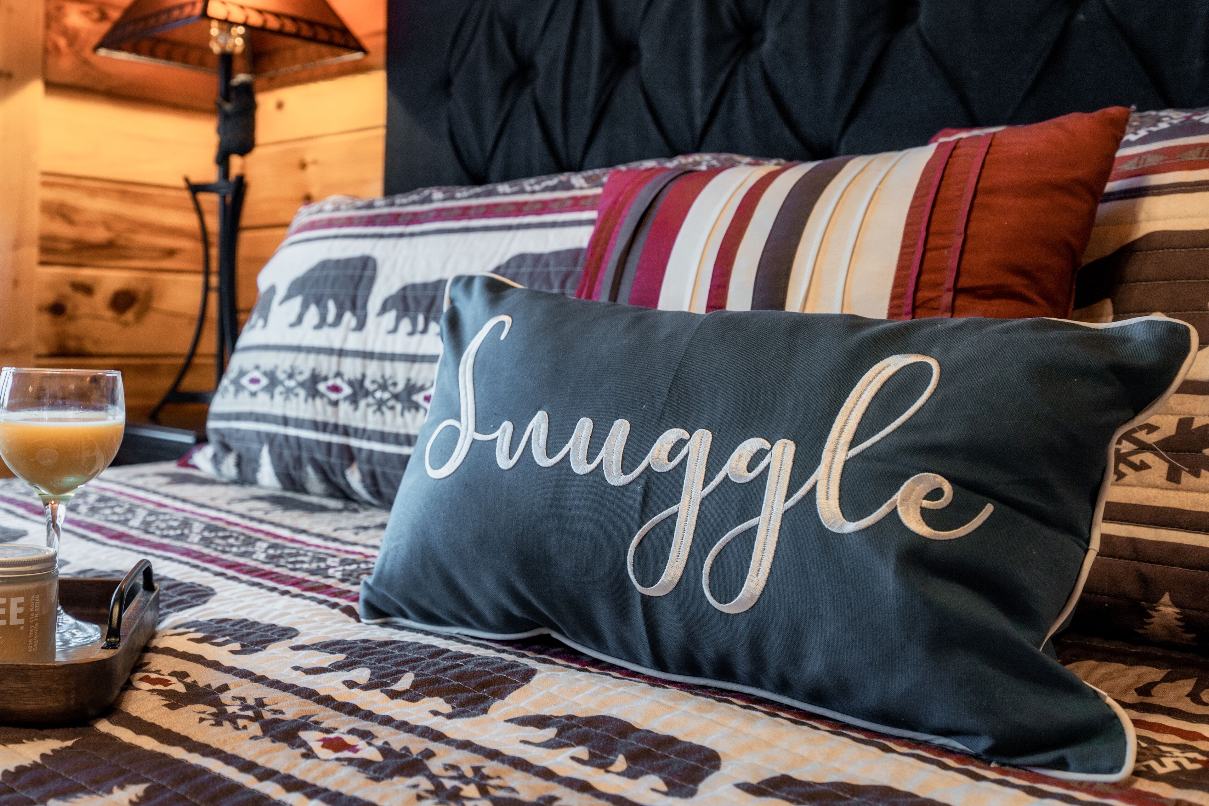 A bed with a pillow labeled "Snuggle," a glass of orange juice, and a tray with a mug.