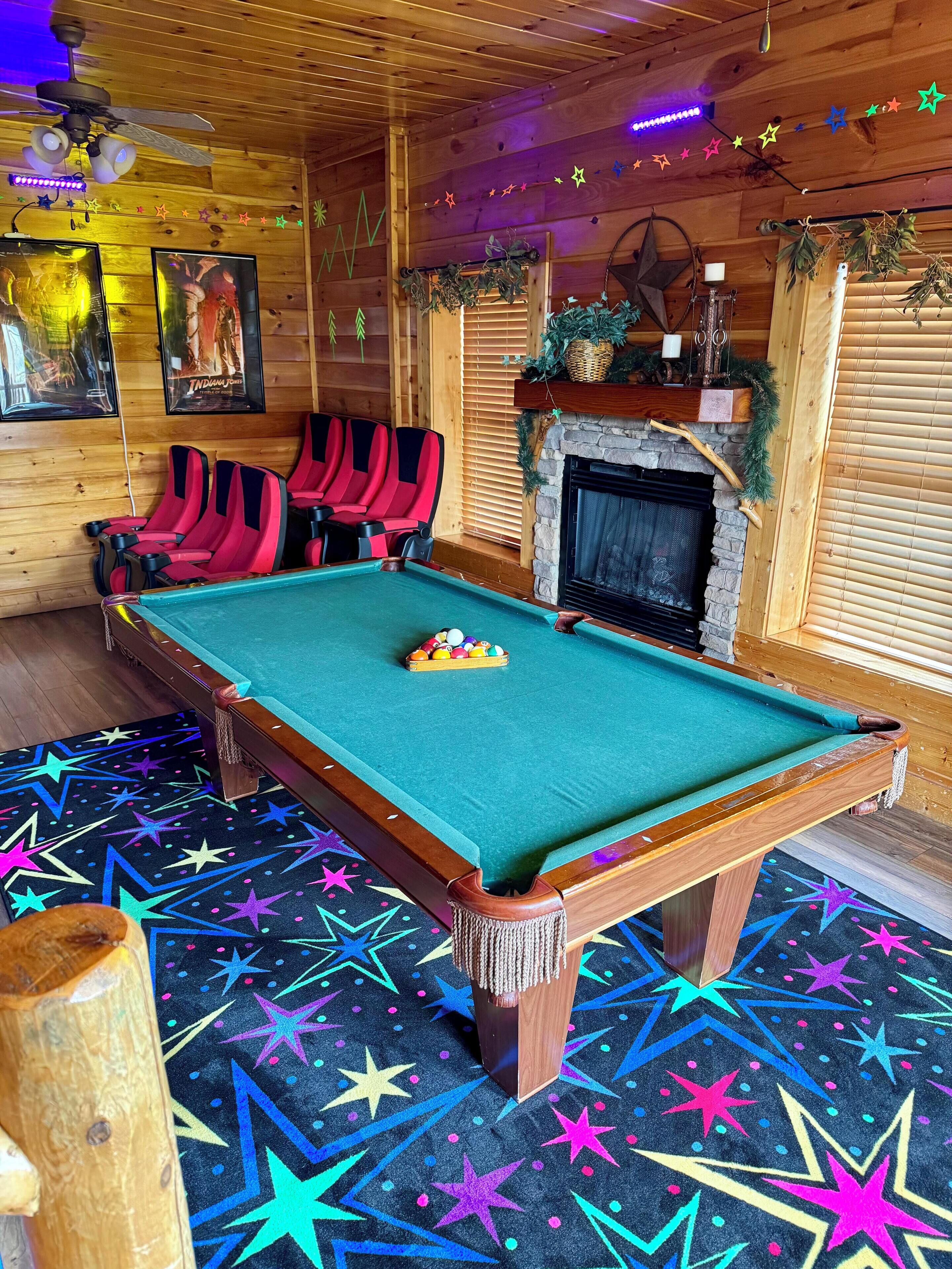 A pool table with red and black chairs, a fireplace, and star-patterned carpet.