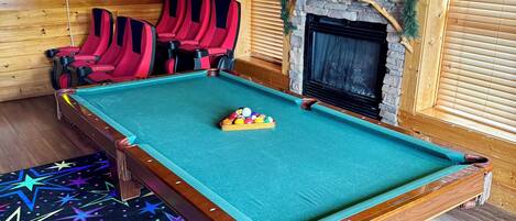 A pool table with red and black chairs, a fireplace, and star-patterned carpet.