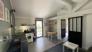 A compact kitchen with a washing machine, a microwave, and a sink. There is a dining area with a table and chairs. - Charming Guesthouse with view to countryside and Mont Ventoux (Entrechaux)