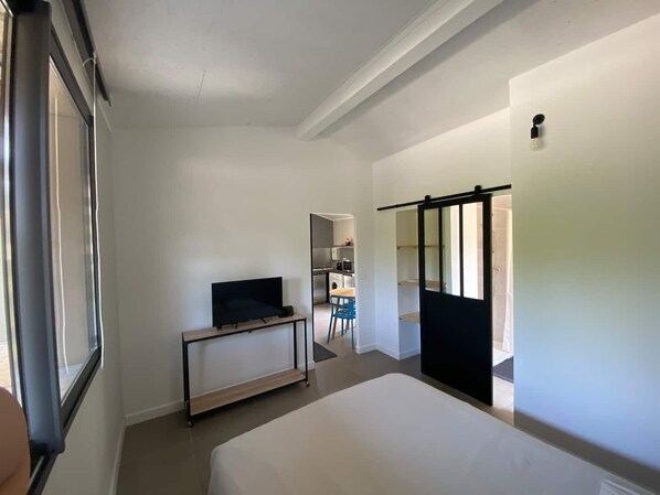 A hotel room with a bed, a desk, a chair, and a TV.