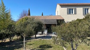 A building with a tiled roof, a covered porch, and a garden with trees and shrubs. - Charming Guesthouse with view to countryside and Mont Ventoux (Entrechaux)