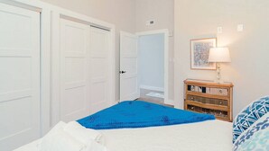 Un dormitorio con una cama, un tocador, una puerta y una lámpara fijada a la pared.