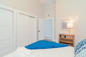 Une chambre à coucher avec un lit, une commode, une porte et une lampe fixée au mur.