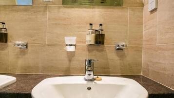 A bathroom with a large sink, a mirror, and toiletries on the wall.