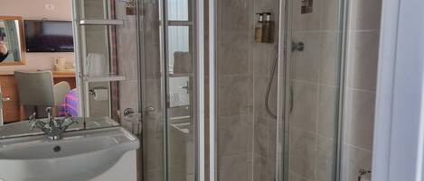A modern bathroom with a glass-enclosed shower, a sink with a mirror, and a toilet.