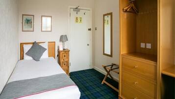 A hotel room with a bed, a dresser, a mirror, and a wardrobe.