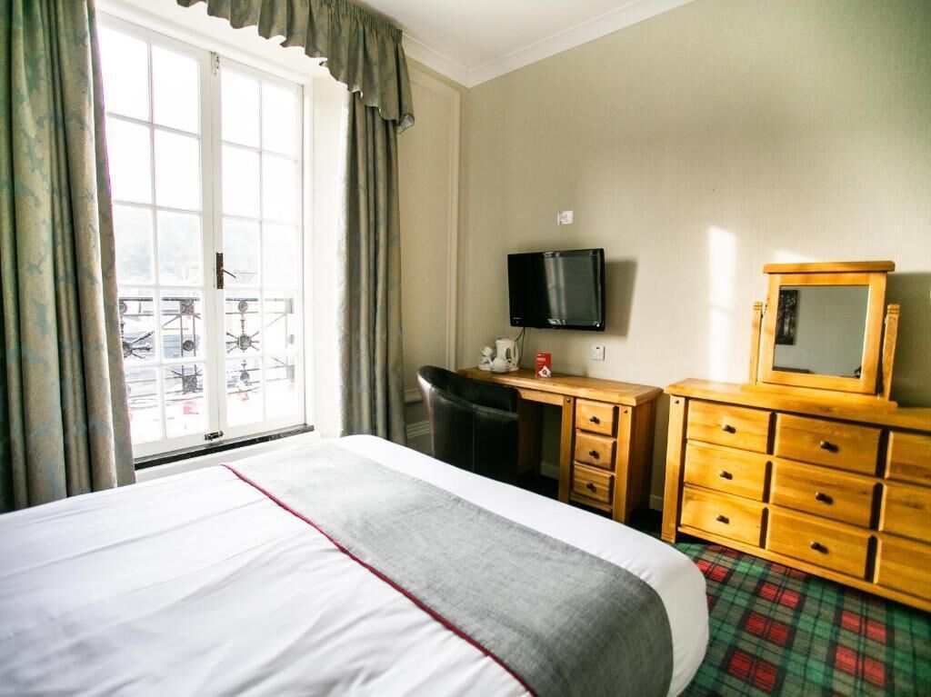 Ein Hotelzimmer mit Bett, Schreibtisch, Fernseher und Kommode.