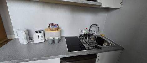 Cocina compacta con microondas, tostadora y lavabo.