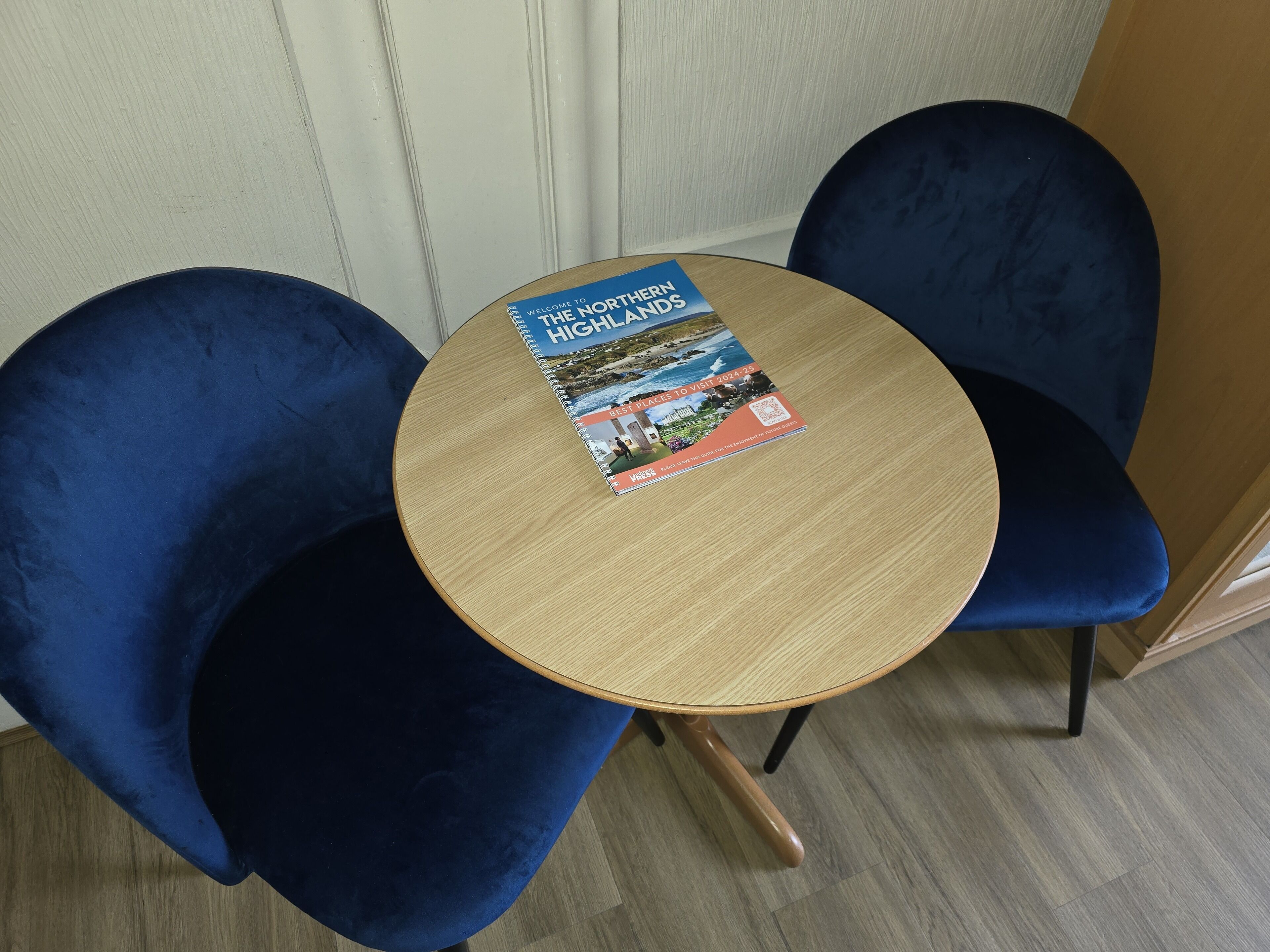 Una mesa de madera redonda con un libro titulado "The Northern Highlands" sobre ella.