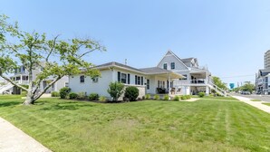 A two-story house with a front porch, a driveway, and a well-maintained lawn. - Bay-View Bungalow, Dogs Welcome, Parking — Sleeps 9, Single Level (Ventnor City)