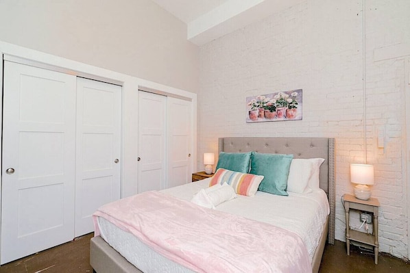 A bedroom with a bed, two bedside tables, a nightstand, and a wall-mounted painting.