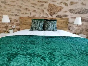 A bedroom with a wooden headboard, two patterned pillows, a teal blanket, and two bedside lamps. - Cantinho Daldeia - Rural House with Pool (Guarda)