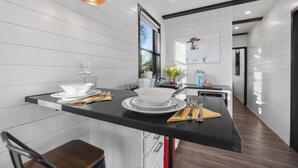 Une cuisine moderne avec des meubles blancs, des plans de travail noirs et des suspensions lumineuses en cuivre.