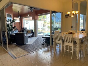 A spacious indoor area with a dining table and chairs, a sofa, and a small table with a lamp.