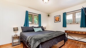 Une chambre moderne avec un lit, des tables de chevet, un banc et une fenêtre avec des rideaux.