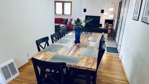Un coin repas avec une table en bois, des chaises noires et un canapé rouge en arrière-plan.