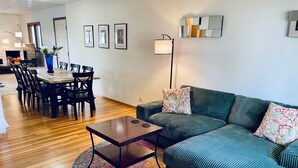 Un salon moderne avec un canapé vert, une table basse et un coin repas comprenant des chaises et une table.