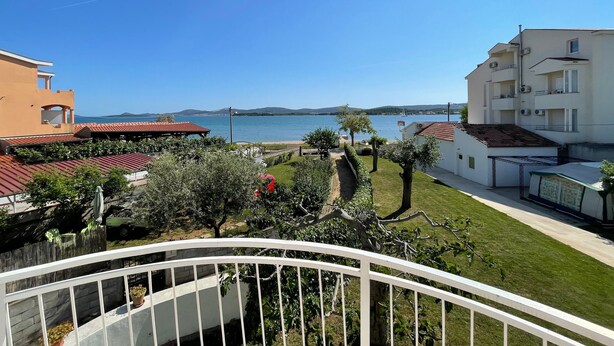 A balcony with a view of a body of water, a bridge, and a hilly landscape in the distance.