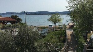 A lakeside property with a pathway leading to a dock, surrounded by greenery and a clear view of the lake.