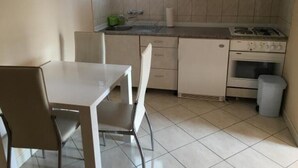 A kitchen with a dining table and chairs, a stove, and cabinets. - Apartments Roko- One bedroom apartment with balcony and sea view (B3) (Sveti Filip i Jakov)