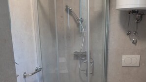 Ein Badezimmer mit Glasdusche, einem weißen Waschbecken und einer Toilette.