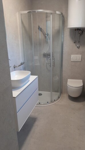Une salle de bain avec une douche à parois de verre, un lavabo blanc et des toilettes.