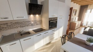 Una cucina moderna con mobili bianchi, forno nero e lavello in acciaio inossidabile.
