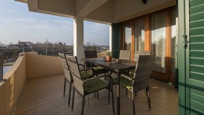 Un balcone con tavolo e sedie, una pianta in vaso e vista sulla città.