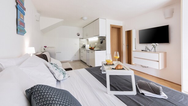 Quarto de hotel moderno com cama, mesa de cabeceira e televisão.