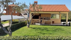 Uma casa moderna com cozinha externa coberta e gramado bem cuidado.