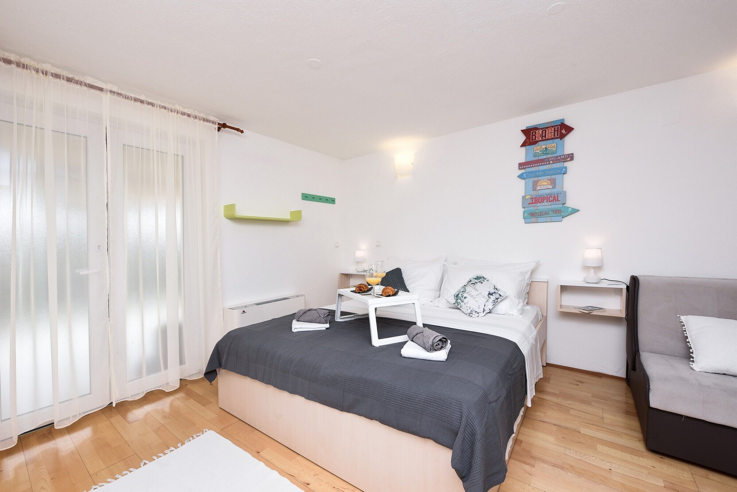 A bedroom with a bed, bedside tables, a nightstand, a window with curtains, and a wall decoration.