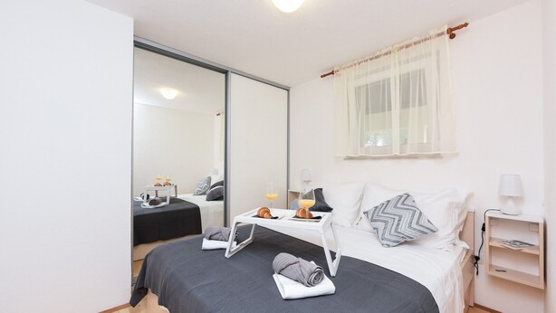 A modern hotel room with a bed, bedside table, and a mirror. - San Pedro Two bedroom apartment with sea view balcony (A2) (Sv. Petar na Moru)