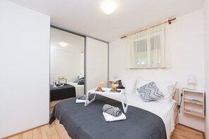 A modern hotel room with a bed, bedside table, and a mirror.