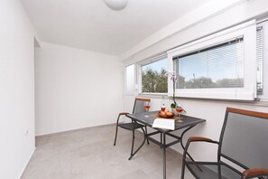 A dining area with a table, chairs, and a window with blinds.