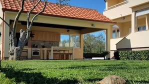 A house with a covered outdoor area, a tree, and a turtle on the grass. - San Pedro Two bedroom apartment with sea view balcony (A2) (Sv. Petar na Moru)
