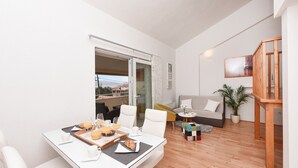 A modern living room with a dining area, a sofa, a coffee table, and a staircase.