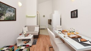 Een moderne, goed verlichte woonruimte met een bank, salontafel en een ontbijtarrangement.
