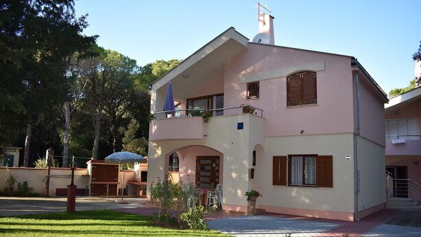 Un bâtiment à deux étages doté d’un balcon, d’un petit jardin et surplombant un ciel dégagé.