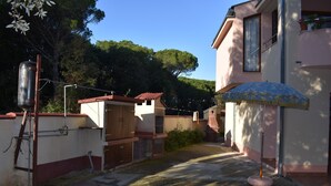 Une rue étroite, avec un petit bâtiment sur la droite, une clôture en bois sur la gauche et un réservoir d’eau en métal.