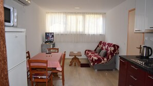 Un espace de vie compact comprenant un coin repas, un canapé, une petite table et une kitchenette.