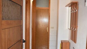 Habitación pequeña con cama integrada, una ventana y estante de madera en el techo.